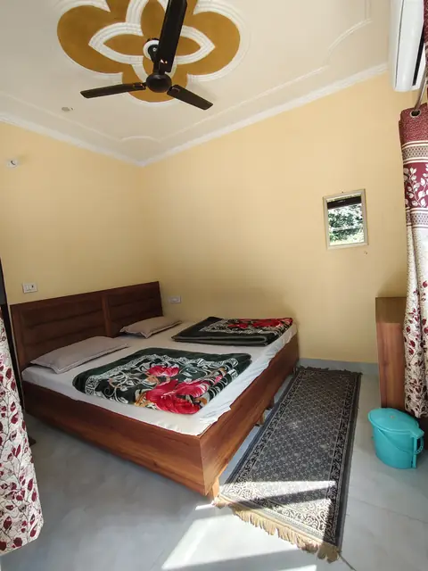 A double room at Ganga Home Stay with a wooden bed, folded blankets and a carved ceiling