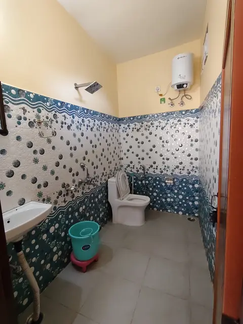 A bathroom with blue and white tiles, a shower and a geyser
