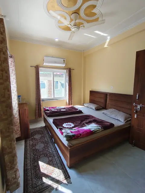 A double room with a wooden bed, an AC and a long rug