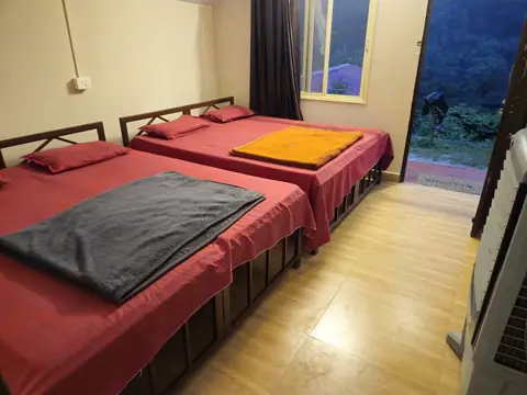 A camp room with two double beds and an air cooler