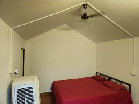 A camp room with a double bed, a ceiling fan and an air cooler