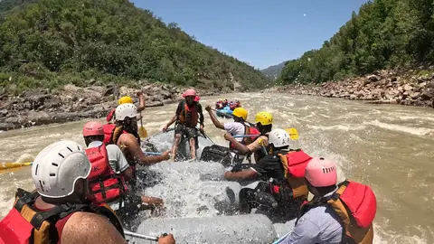 The crew cheers as the raft rides through a rapid, with more rafts behind