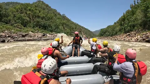The raft rides through a rapid as the paddlers raise their fists