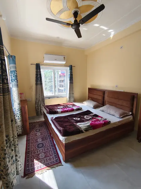 A double room with a wooden bed, an AC and a red rug