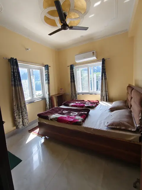 A bright double room with two windows, an AC and a view of the hills